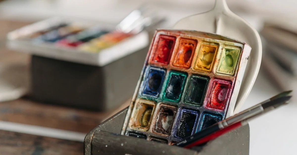Peintures aquarelles vibrantes et pinceaux dans un studio d'artiste, prêts pour la créativité.