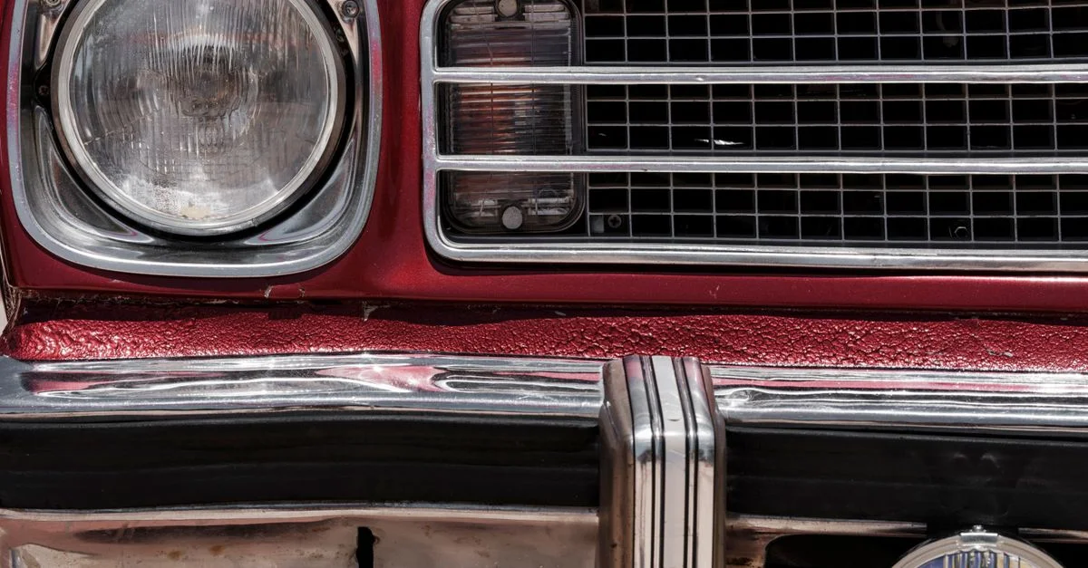 Vue détaillée d'une calandre et de phares de voiture classique vintage rouge.