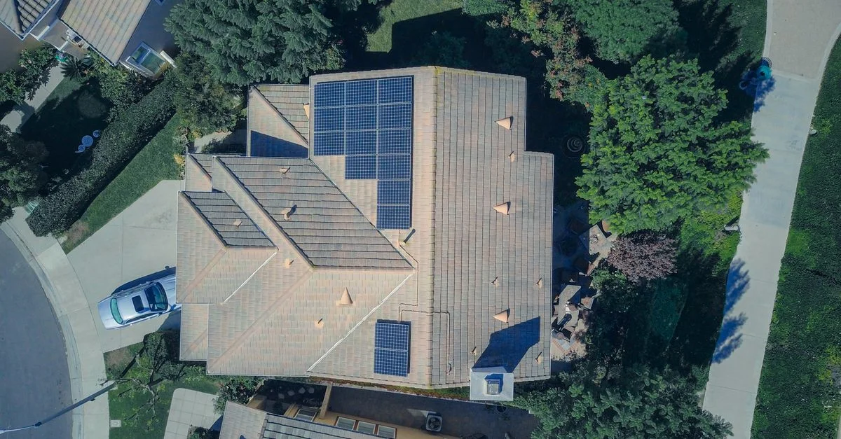 Vue aérienne d'une maison avec panneaux solaires, mettant en avant des solutions modernes d'énergie renouvelable.
