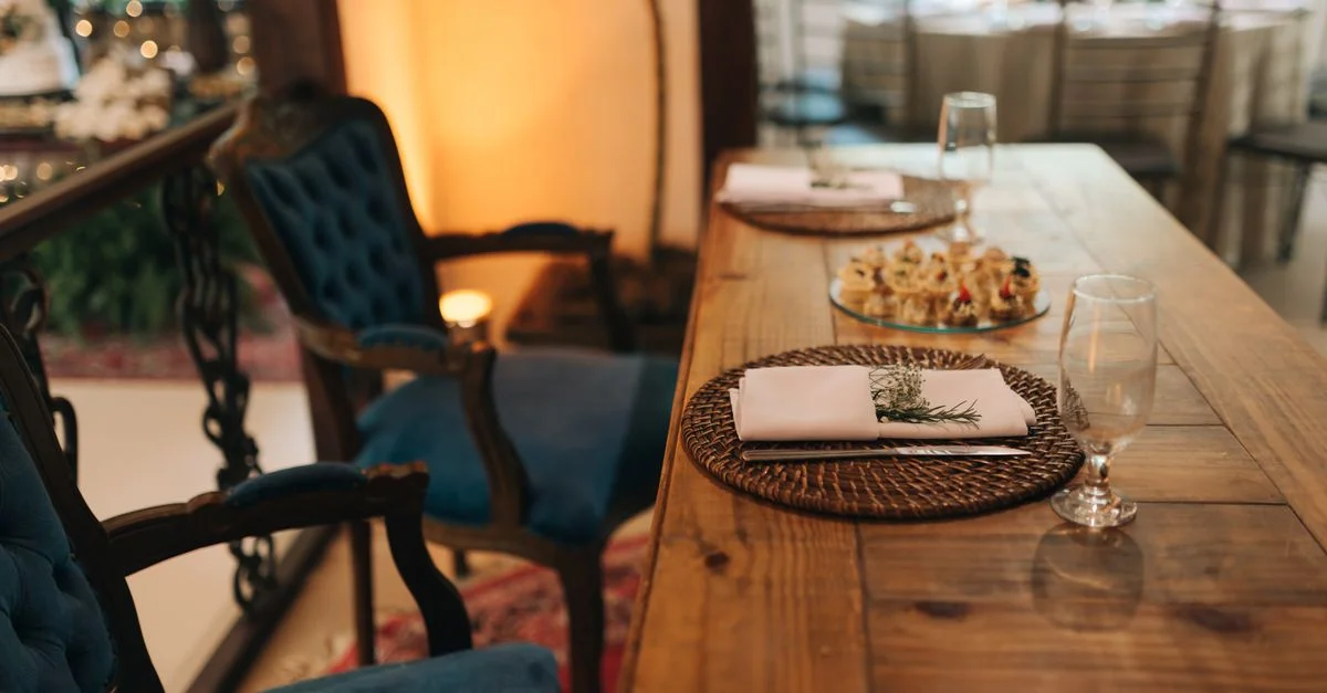 Une mise en place de dîner intérieure sophistiquée avec des chaises en velours bleu et une décoration de table en bois.
