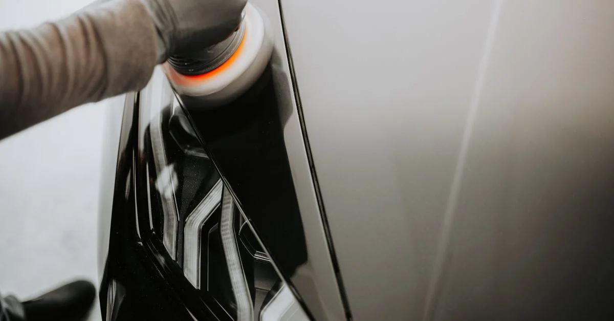 Vue en gros plan d'une personne polissant une voiture noire à l'aide d'une machine à polir.