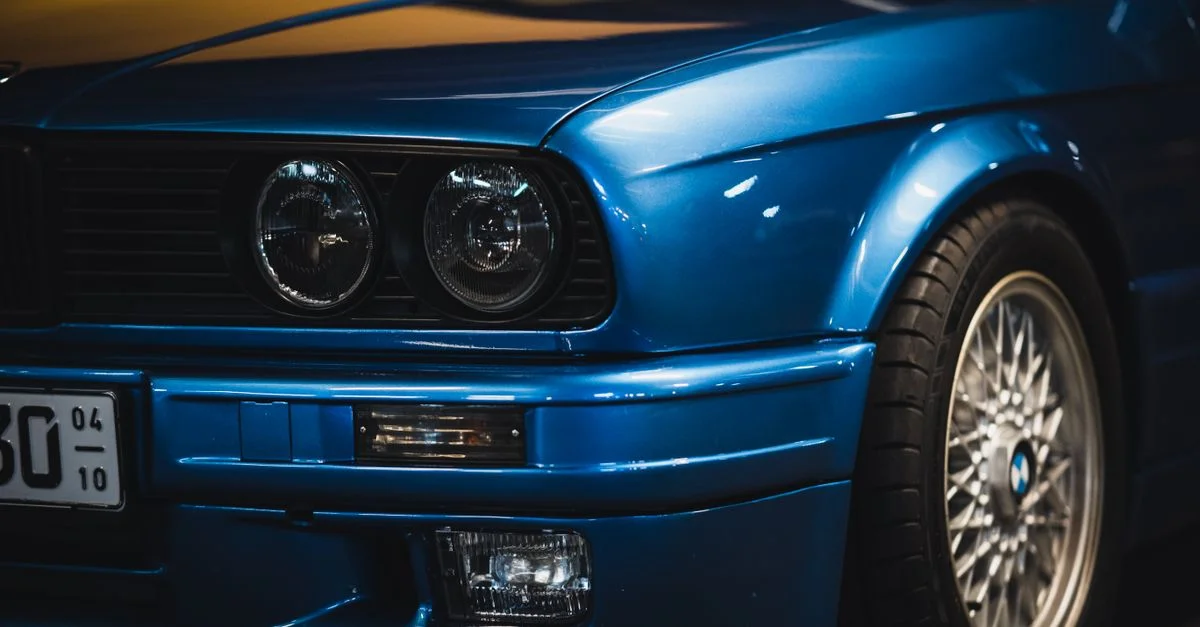 Gros plan sur l'avant d'une voiture classique bleue avec des phares et un design élégant.
