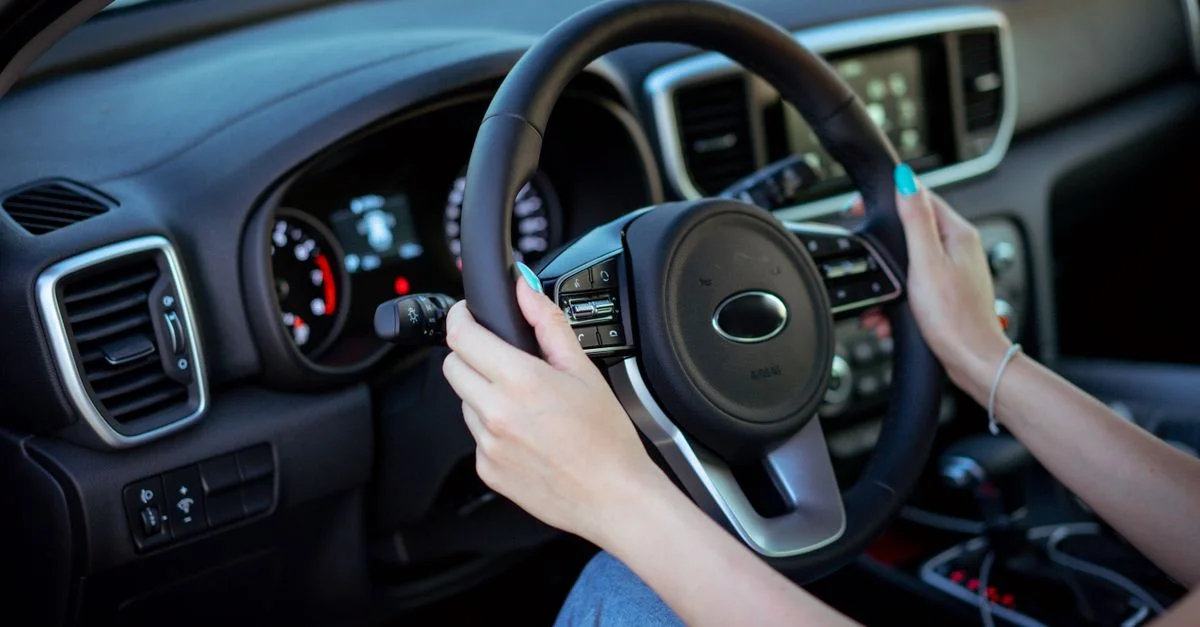 Gros plan des mains d'une femme sur un volant dans l'intérieur moderne d'une voiture.