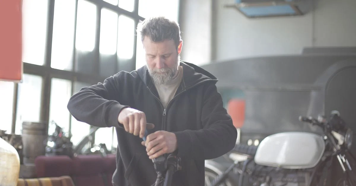 Un mécanicien dévoué répare une moto dans un atelier lumineux et ensoleillé.